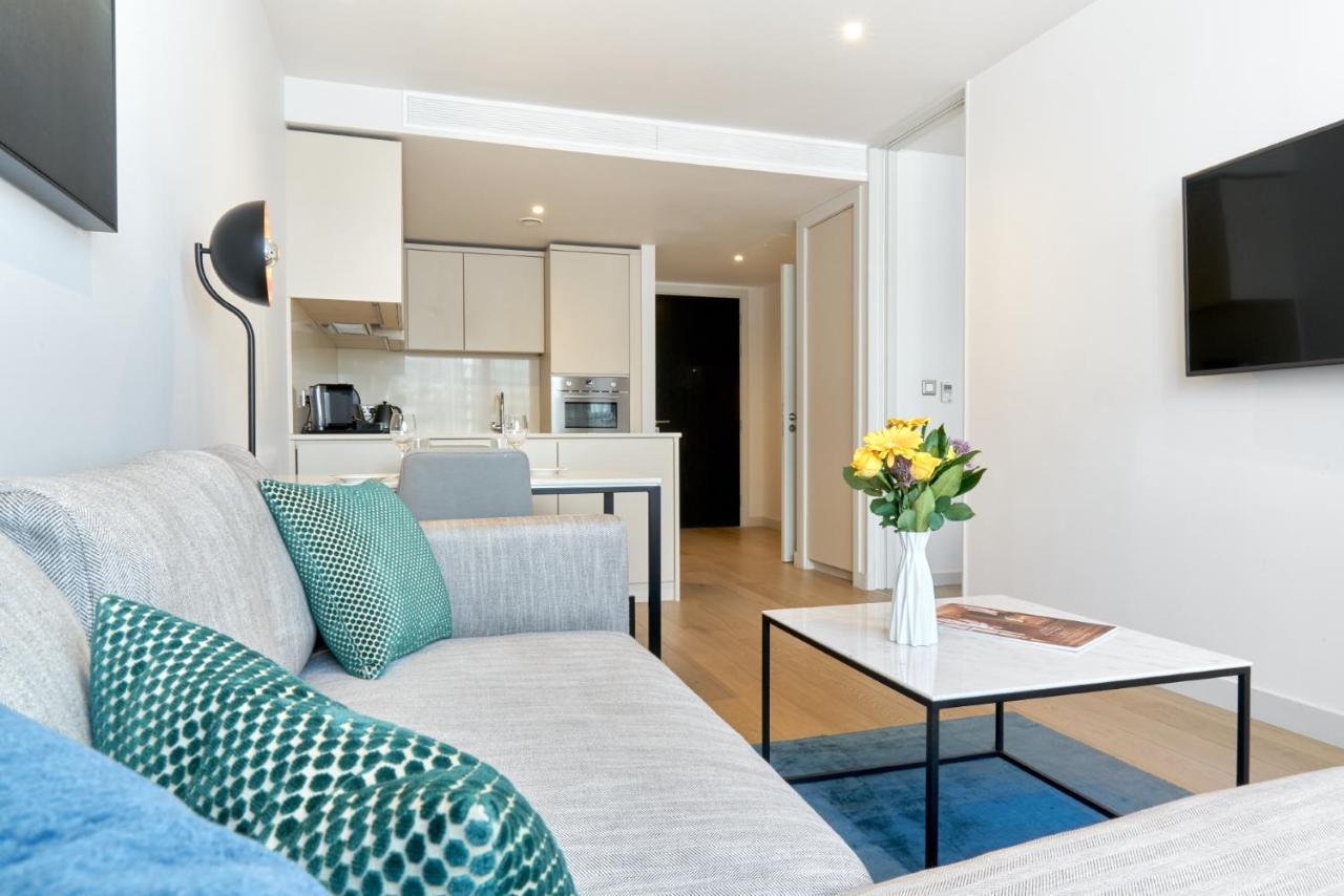 Citysuites Aparthotel Manchester Esterno foto The photo shows a modern and stylish living space. On the left, there is a light gray couch adorned with decorative pillows, including a blue one and a green patterned one. In front of the couch, there is a sleek coffee table with a vase of fresh flo