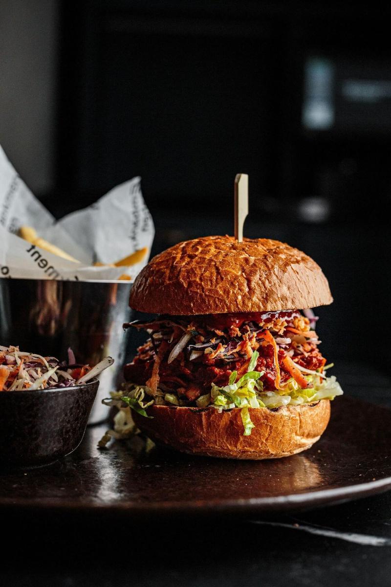 Citysuites Aparthotel Manchester Esterno foto The photo features a hearty hamburger stacked high with various ingredients. The bun appears to be a toasted, golden-brown color. Inside, there's a generous portion of shredded meat, likely barbecued or pulled. The burger is topped with fresh vegetab
