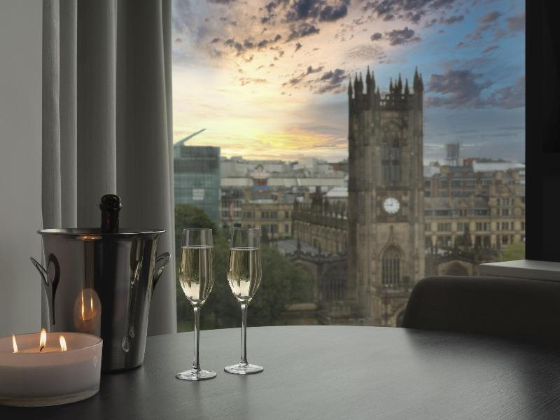 Citysuites Aparthotel Manchester Esterno foto The photo shows a cozy indoor setting with a table that features two champagne glasses and a bottle of champagne in an ice bucket. There is also a lit candle on the table, enhancing the intimate atmosphere. In the background, large windows reveal a c