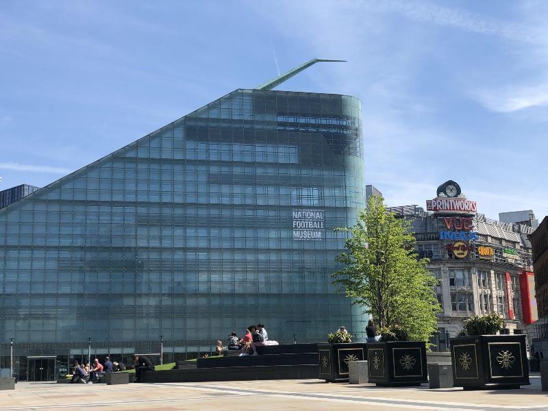 Citysuites Aparthotel Manchester Esterno foto The photo shows a modern, glass-paneled building with an angular design. This structure features a large, sloping roof and appears to be a public building, possibly a museum given the visible text that suggests “NATIONAL FOOTBALL MUSEUM.” In front of