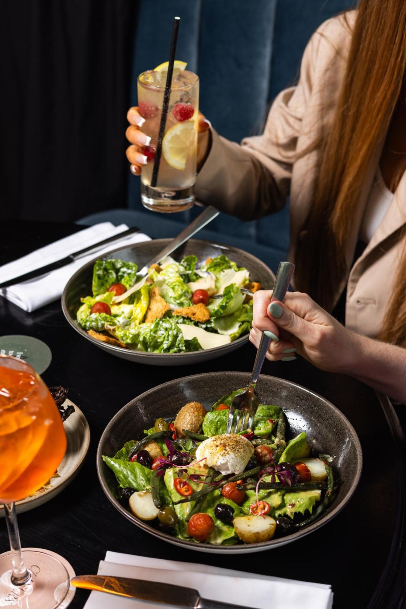 Citysuites Aparthotel Manchester Esterno foto The photo shows a dining scene with two dishes on a table. One bowl contains a vibrant green salad with romaine lettuce, cherry tomatoes, and possibly other fresh ingredients. The other bowl features a mixed salad with various colorful vegetables and