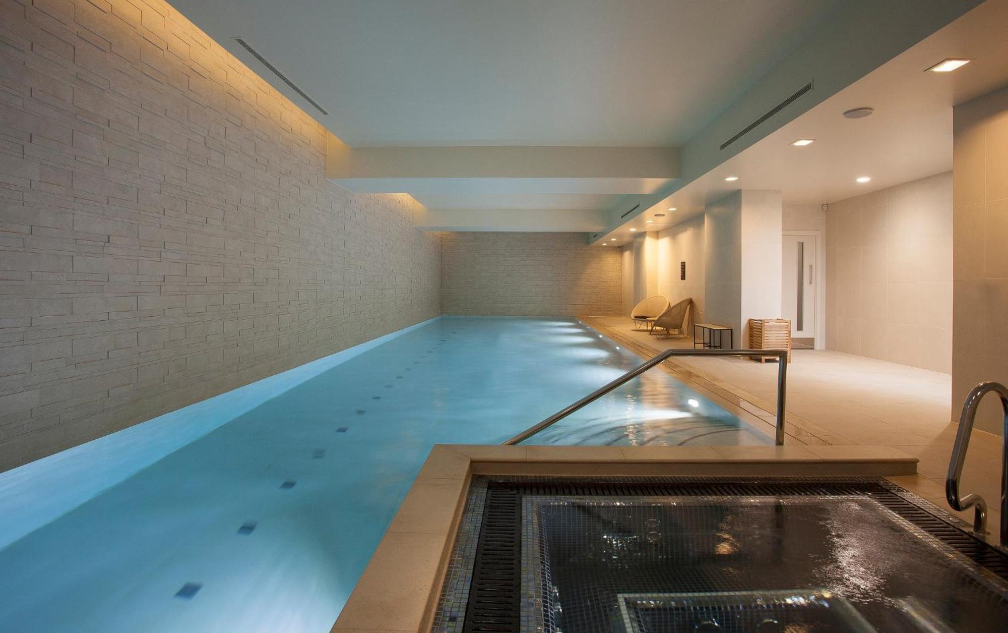 Citysuites Aparthotel Manchester Esterno foto The photo shows a serene indoor swimming pool area. The pool is rectangular and features calm, clear water. On one side, there are steps leading into the pool, and the surrounding walls are made of light-colored bricks, contributing to a tranquil amb