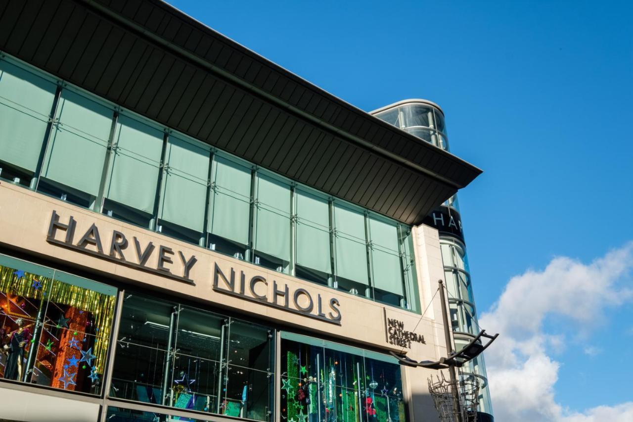 Citysuites Aparthotel Manchester Esterno foto The photo shows the exterior of a retail building featuring the name "Harvey Nichols" prominently displayed. The architecture includes large glass windows, and the design appears modern and sleek. The sky above is bright blue, suggesting a sunny day,