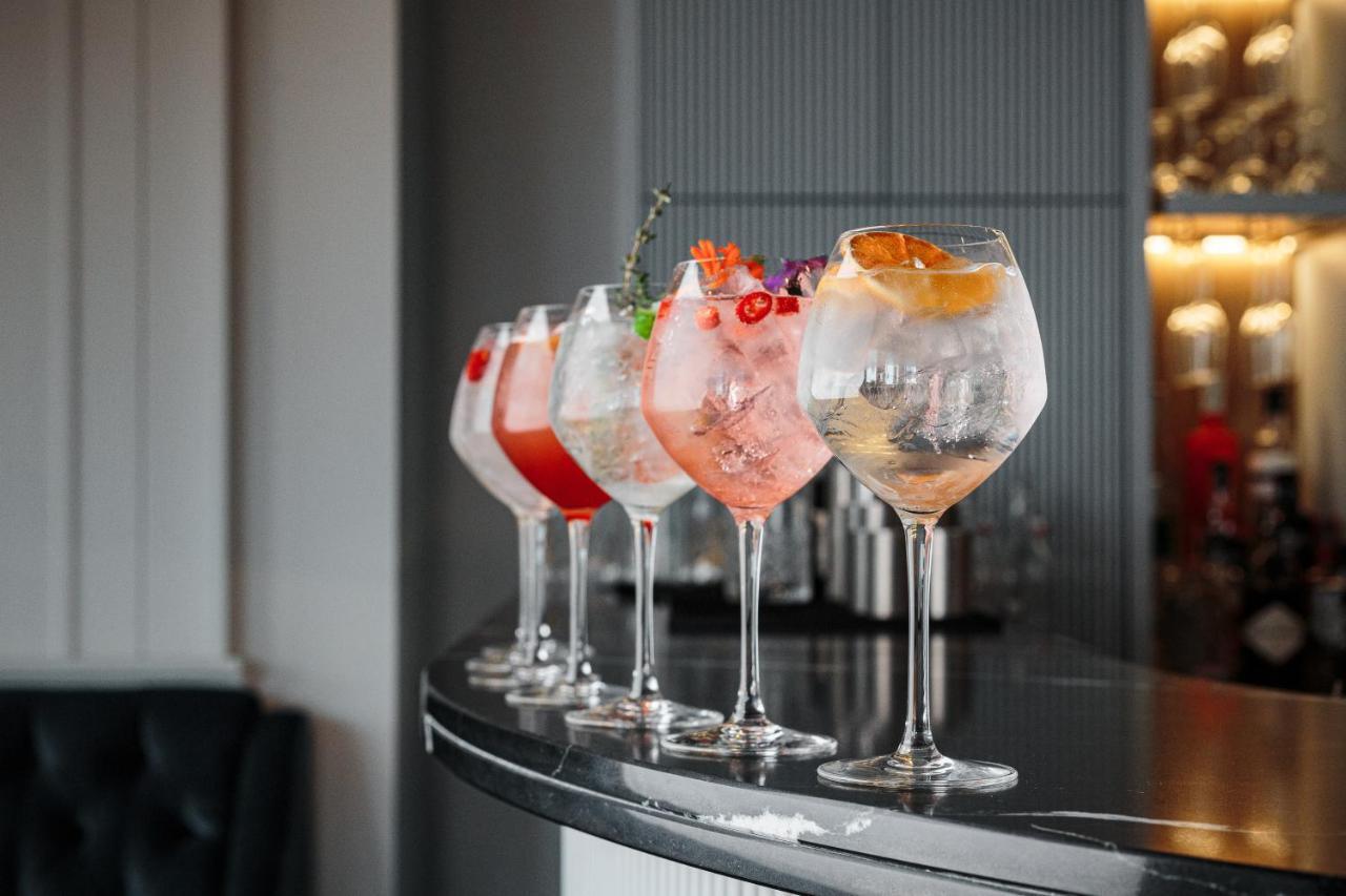 Citysuites Aparthotel Manchester Esterno foto The photo shows a selection of five elegant cocktails arranged neatly on a bar counter. Each cocktail is served in a large, round glass and features different colors and garnishes. 

- The first cocktail on the left appears to have a red hue with gar